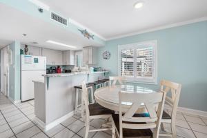ガルフ・ショアーズにあるClearwater 2Aのテーブルと椅子と冷蔵庫のあるキッチン +28枚の写真