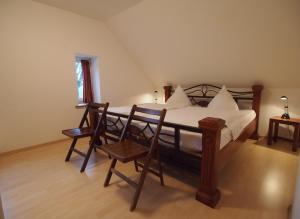 a bedroom with a bed with two chairs and a table at Gut Rattelvitz, Galerie F WEST in Gingst