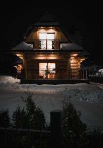 een groot houten huis met een terras in de sneeuw bij Przewodnicka Chata in Kościelisko