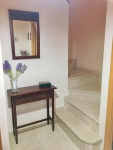 einen Flur mit einem Tisch, einem Spiegel und einer Treppe in der Unterkunft Amplio adosado a 5 mits del metro y centro comercial in Mairena del Aljarafe + 19 Fotos