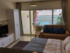 a bedroom with a bed and a couch and a balcony at Cozy, Calm, Studio in Veranda Sahl Hasheesh Resort in Hurghada
