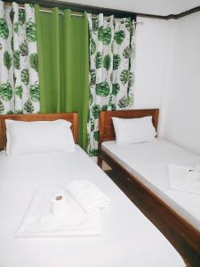 two beds in a room with green and white curtains at Ziah's Guest House in San Vicente