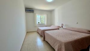 two beds in a white room with a window at Altura Beach Apartment in Altura