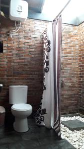 a bathroom with a toilet in front of a brick wall at omah linares in Celep