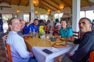a group of people sitting around a table at Laguna de Cuicocha Guest House in Urcusiqui