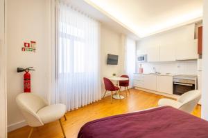 ein Schlafzimmer mit einem Bett und Stühlen sowie eine Küche in der Unterkunft Try Oporto - São Lázaro in Porto