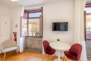 ein kleiner weißer Tisch und Stühle in einem Raum mit einem Fenster in der Unterkunft Try Oporto - São Lázaro in Porto