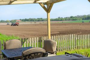 une table et des chaises et un champ avec un tracteur dans l'établissement Vella, à Lincoln