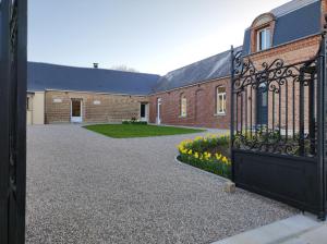 an open gate to a brick building with flowers at Le clos des Prêles in Boismont