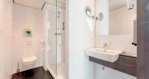a white bathroom with a sink and a toilet at PLAZA Premium Almere in Almere +119 photos