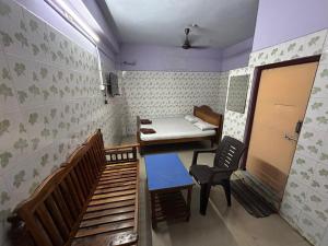 a small room with a bed and a table and chairs at Meera Lodge in Chidambaram