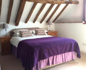 a bedroom with a bed with purple sheets and pillows at Woodman's Barn with countryside views - Sleeps 6 in Norwich