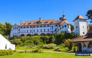 ein großes weißes Gebäude auf einem Hügel in der Unterkunft Swiss Cottage in Tenby
