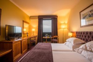 a hotel room with a bed and a flat screen tv at Vila Gale Porto - Centro in Porto +36 photos