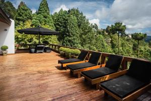 une terrasse en bois avec des chaises et un parasol dans l'établissement Aberdeen Premium Stay, à Campos do Jordão