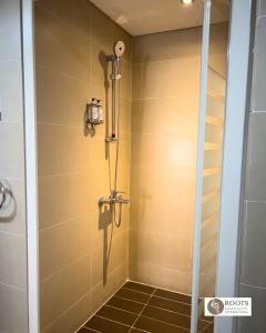 a shower in a bathroom with a glass door at Roots Hotel Apartment in Accra