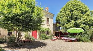 a house with a tree and a green umbrella at Aux Caprices des Dieux in Marnes