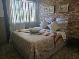 Un dormitorio con una cama con una pared de ladrillos. en De Adelaar Landgoed, en Cullinan 36 fotos más