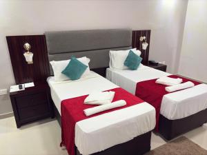 two beds in a hotel room with towels on them at Dikukama Executive Hotel in Tshabong +1 photo