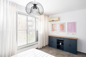 a bedroom with a blue cabinet and a large window at Best Location 3BR Specious Apartment By Vacay in Tel Aviv