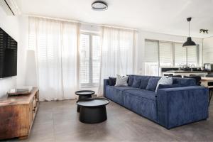 a living room with a blue couch and a table at Best Location 3BR Specious Apartment By Vacay in Tel Aviv