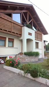 a house with a balcony and flowers in front of it at B&B San Giorgio in Sovramonte