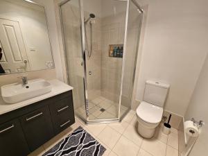 a bathroom with a shower and a toilet and a sink at Blissful Modern 5 BR Lux Style Family House in Marsden Park +25 photos