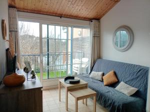 a living room with a blue couch and a balcony at Studio port, lac, plage in Talmont