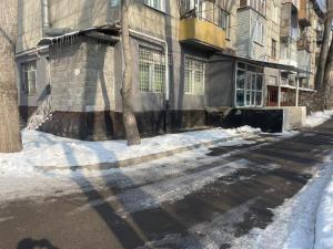 an empty street with snow on the side of a building at Хостел in Almaty