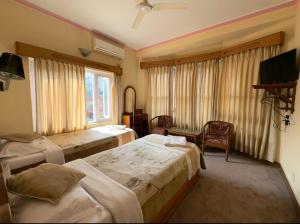 um quarto de hotel com duas camas e uma televisão em Green Tara Hotel em Pokhara