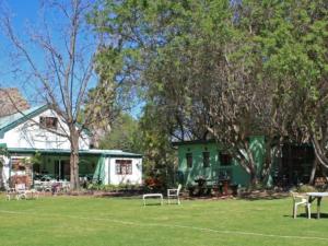 a green house with tables and chairs in a yard at Rainbow Glen Self Catering Chalets in Montagu +11 photos