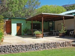 a house with a stone wall and a patio at Rainbow Glen Self Catering Chalets in Montagu