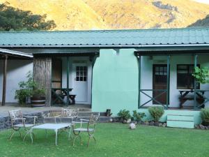 a blue house with a table and chairs in the yard at Rainbow Glen Self Catering Chalets in Montagu
