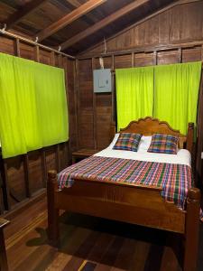 a bedroom with a wooden bed with green curtains at Green Jay Cabins in Duffy Bank