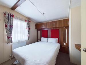 a bedroom with a large white bed and a window at TOM TODDY - Enchanting Golden Sands Caravan at Dawlish Warren in Dawlish Warren
