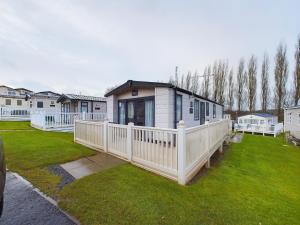 a small house with a white railing on a yard at TOM TODDY - Enchanting Golden Sands Caravan at Dawlish Warren in Dawlish Warren