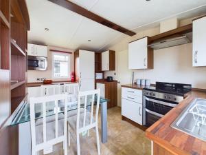 a kitchen with white cabinets and a table and chairs at TOM TODDY - Enchanting Golden Sands Caravan at Dawlish Warren in Dawlish Warren