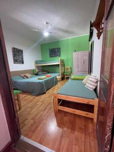 two beds in a room with green walls and wooden floors at Casa Mboyeré in Concepción del Uruguay