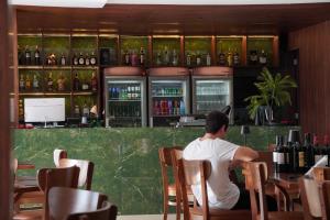 a man sitting at a bar in a restaurant at Wai Hotel Picos in Picos