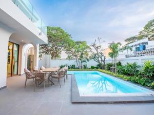 a patio with a table and chairs and a swimming pool at So beach villa pattaya in Jomtien Beach