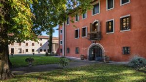 a large red building with a tree in front of it at Villa Chiopris in Chiópris-Viscone