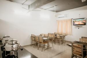ein Esszimmer mit Tischen und Stühlen und einem Fernseher in der Unterkunft RD HOTEL-Bhavani Road in Erode
