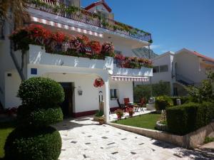 a white house with flowers on the balcony at Apartments Tomic in Dugi Rat