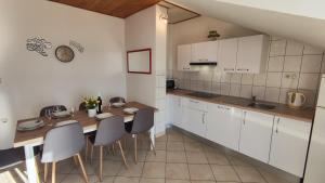 a kitchen with white cabinets and a wooden table and chairs at Apartments Tomic in Dugi Rat