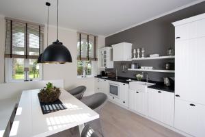 a kitchen with white cabinets and a white table at Zollhaus 1 in Keitum