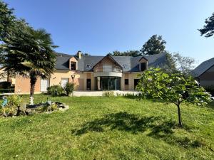 a large house with a palm tree in the yard at Villa Nausicaa - Circuit des 24h du Mans - Piscine in Arnage