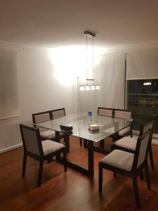 Penthouses Rocas de Santo Domingo Barrio Golf في سانتو دومينغو: غرفة طعام مع طاولة وكراسي زجاجية