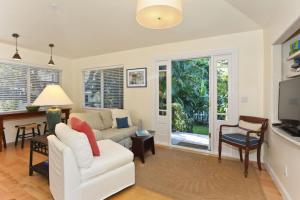 a living room with a white couch and a tv at The Yellow Cottage in Lanikai Your Perfect Island Getaway! in Kailua
