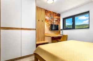 沃拉里Apartmány Na výsluní Šumava - U lípy的一间卧室，配有一张床、一张书桌和一扇窗户