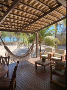 a porch with a hammock and chairs on a beach at KiteHouseArpoeiras in Acaraú